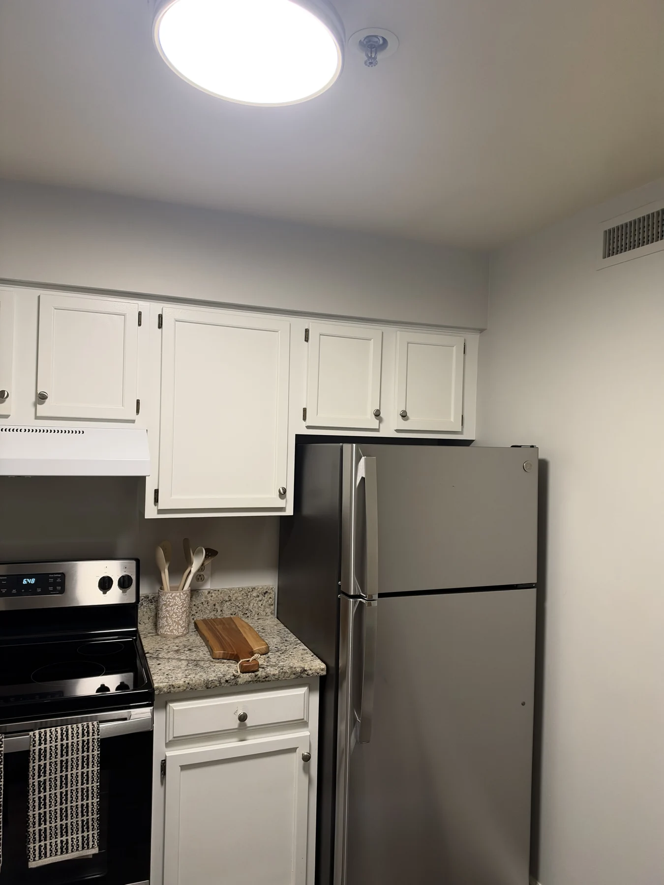 Apartment kitchen with white cabinetry, counters and stainless appliances at Richmond Place